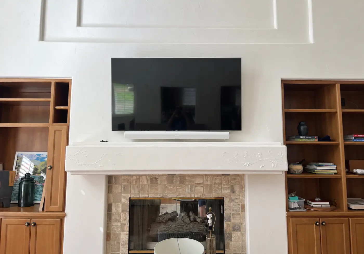 Television and soundbar mounted above a fireplace